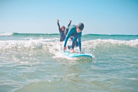 Surf instructor Derek gently pushes the kids into the waves