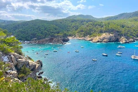 A breathtaking view from a high vantage point, revealing a stunning bay with turquois waters and lush hills.