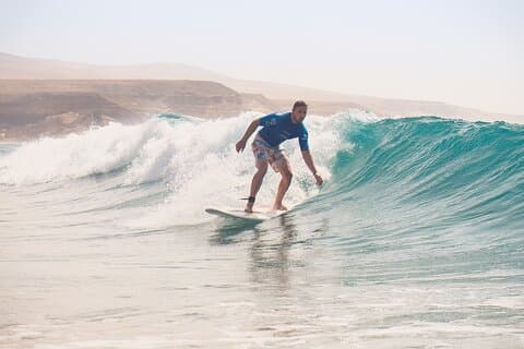 A surfer rides a clean, shoulder-high wave on the west coast of Fuerteventura.