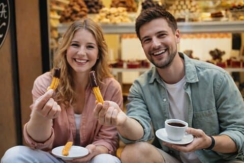 Two tourists eating churros with hot chocolate on a Barcelona food tour