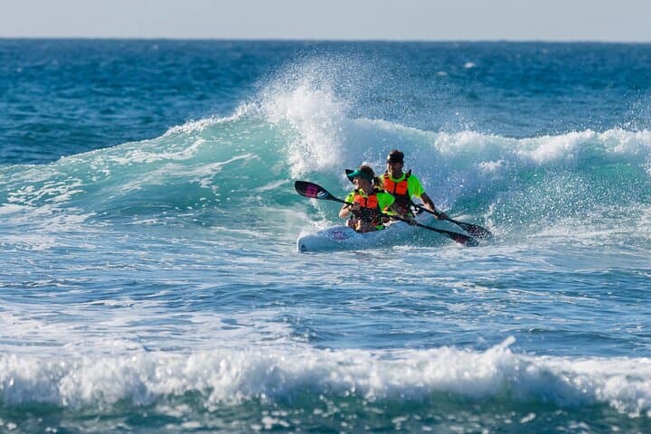 Two paddlers surfing a wave in the south of Gran Canaria (Maspalomas) in double sea canoe (surfski)