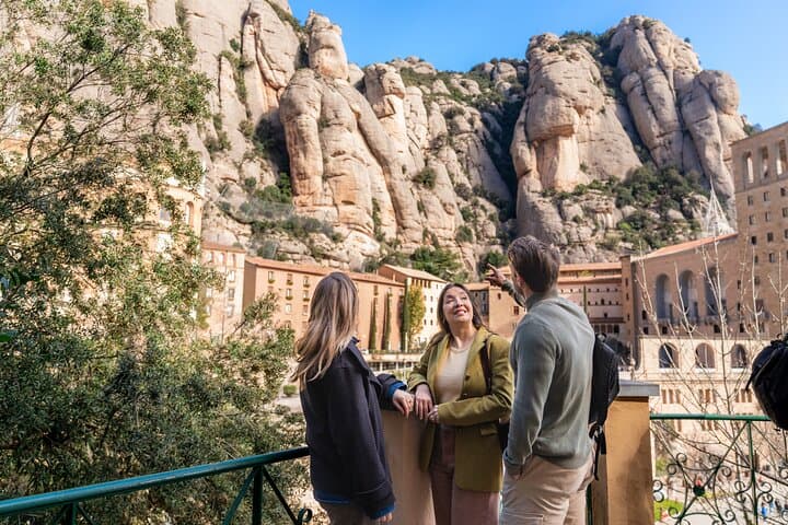 Travelers admire the stunning rock formations of Montserrat Mountain during a guided tour from Barcelona, with Montserrat Monastery nestled below the cliffs