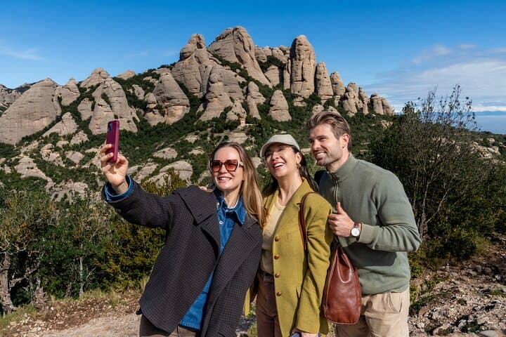 Happy travelers capture a selfie with the iconic Montserrat mountain range in the background during a scenic hiking tour near the monastery
