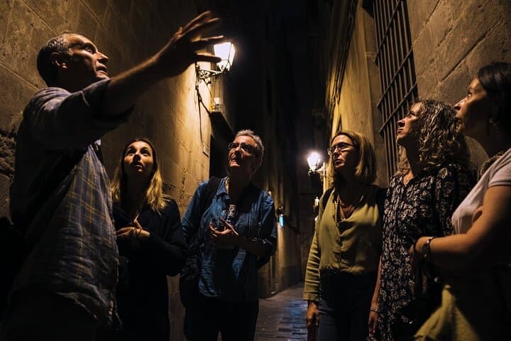 Tour guide telling a story about the spanish inquisition in one of the dark alleys of the old town in Barcelona
