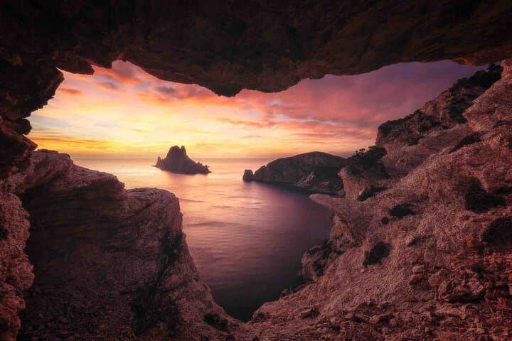 Magical sunset view of Es Vedrà seen from a hidden cave