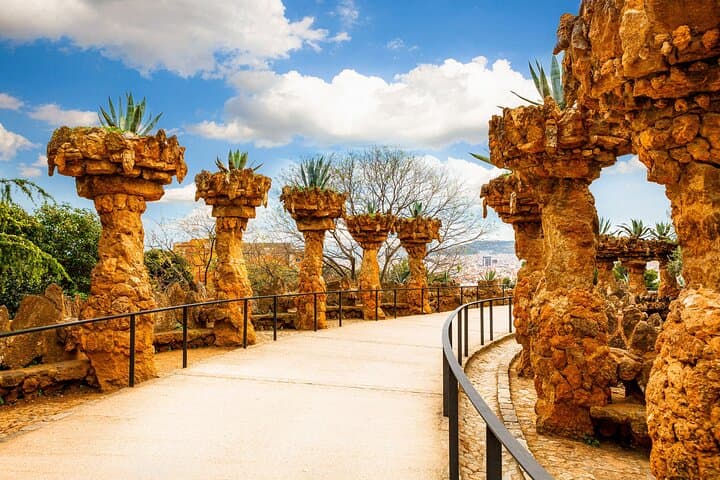 Discover winding pathways and stone columns in Park Güell, showcasing Gaudí’s harmony with nature.