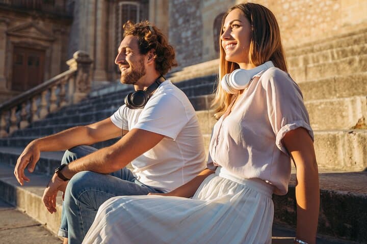 Traveler couple having enjoyed captivating audio stories through their self guided tour in Malaga, now taking a break soaking in the beautiful historic sight.