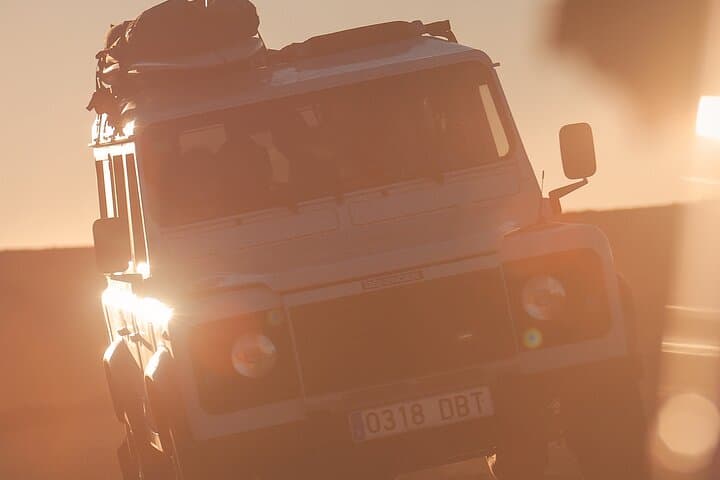 Land Rover Defender drives to a remote surf spot in the morning sun.