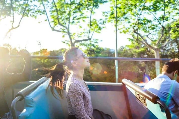 Passengers relax, enjoying the refreshing open-top atmosphere while exploring Barcelona’s lively urban landscape