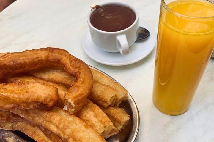 Freshly made churros with chocolate and orange juice in a historic Malaga café