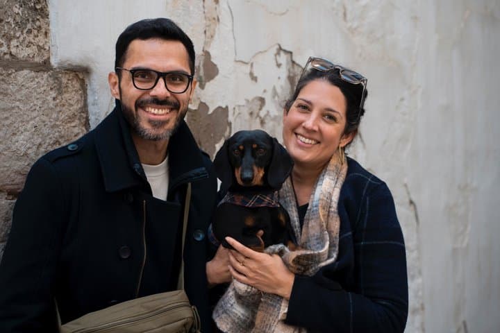 Happy Couple with Sausage dog in the old town of Sitges with white wall in the background.