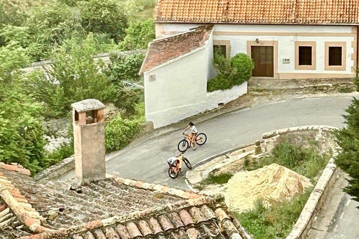 Aerial view of two cyclists riding the streets of Sepulveda between Arab tile roofs and stone houses.
