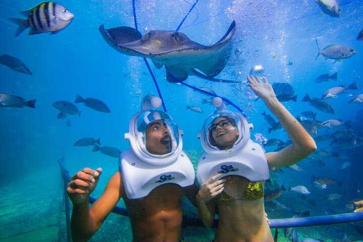 Couple enjoying a magical Sea Trek underwater walk with a manta ray—no swimming required.