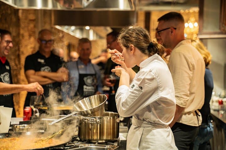 A hands-on moment in our paella class! Students gather around as Chef Maria (my daughter) perfects the dish. This is the authentic, interactive experience you'll book.